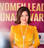 A woman wearing an orange top, smiling